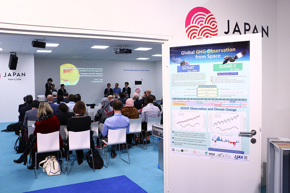 A poster of the comparison of the strengthes on GOSAT and GOSAT-2 projects posted on the door of the conference room in Japan pavilion